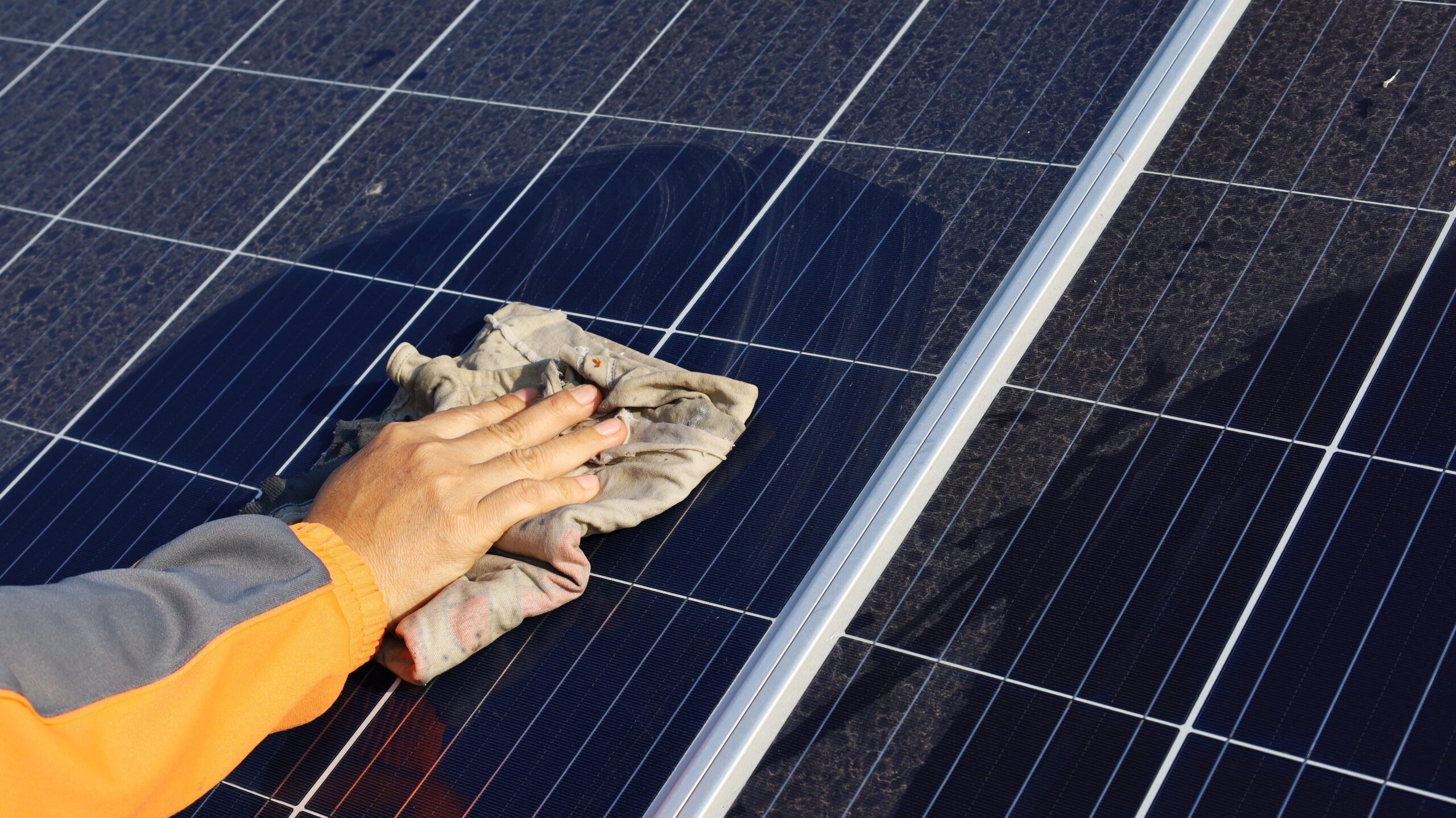 Hand cleaning solar panels. A woman's hands use a towel to wipe
